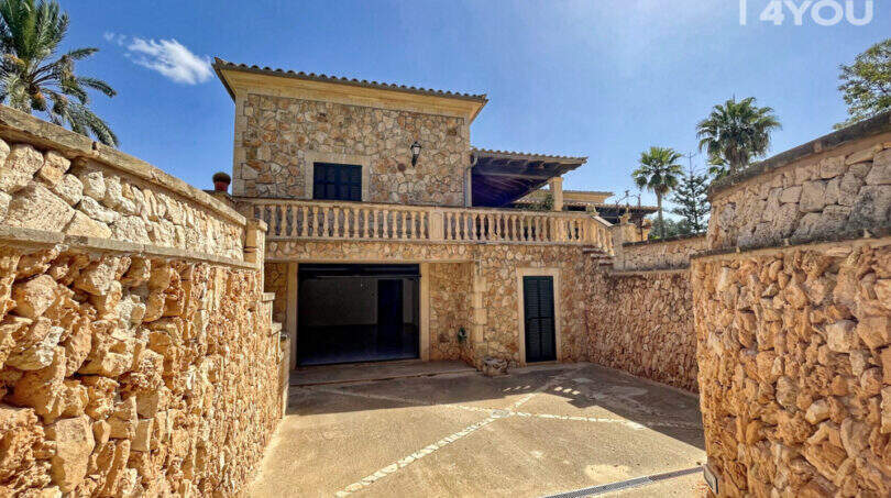 Einfahrt zur exklusiven Finca in Colònia de Sant Jordi mit Natursteinmauern, Garage und Balkon.