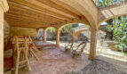 Überdachte Terrasse mit Steinbögen, Holzbalkendecke und Rattanmöbeln der exklusiven Finca in Colònia de Sant Jordi