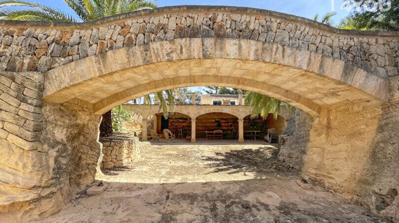Rustikaler Steinbogen am Eingang der exklusiven Finca in Colònia de Sant Jordi mit Blick auf Arkaden