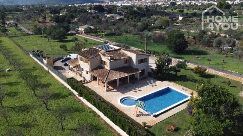 Luftaufnahme einer mallorquinischen Villa in Lloseta mit großem Salzwasserpool, Terrasse und grünem Garten.