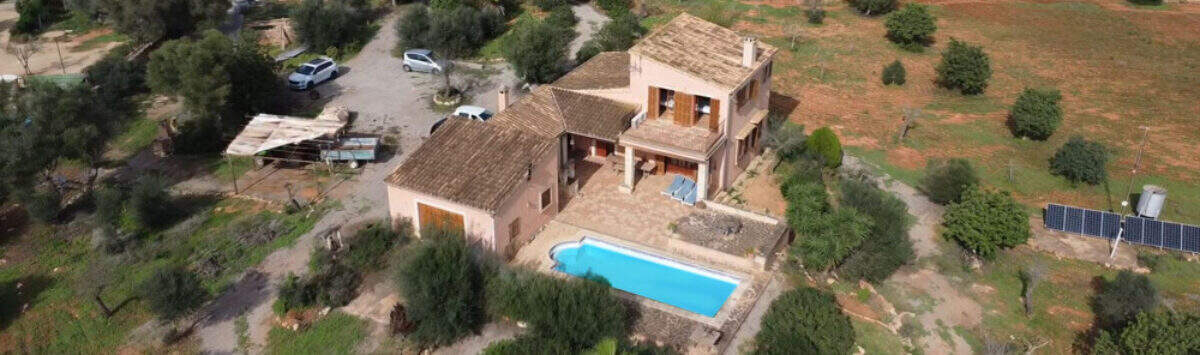 Luftaufnahme einer Finca in Ses Salines mit Pool, Garage und Solaranlage, umgeben von Olivenbäumen.