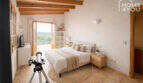 Helles Schlafzimmer der Finca in Ses Salines mit Holzbalkendecke, Doppelbett, Balkon und Natursteinboden.