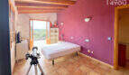 Schlafzimmer mit lila Wand, Holzbalkendecke, Balkonzugang & Meerblick in Finca Ses Salines