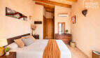 Schlafzimmer der Finca Ses Salines mit Holzbalkendecke, Doppelbett, Klimaanlage und mediterranem Stil