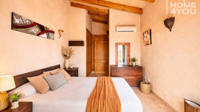 Schlafzimmer der Finca Ses Salines mit Holzbalkendecke, Doppelbett, Klimaanlage und mediterranem Stil