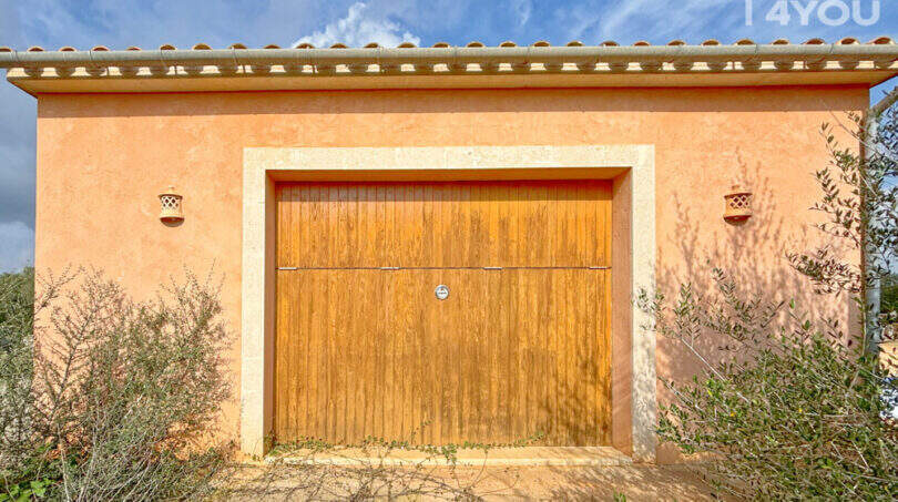Garage der Finca in Ses Salines mit Holztor, mediterranem Putz und Terrakotta-Dach