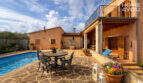 Finca Ses Salines: Sonnige Poolterrasse mit Naturstein, Schmiedeeisenmöbeln und rustikaler Fassade.