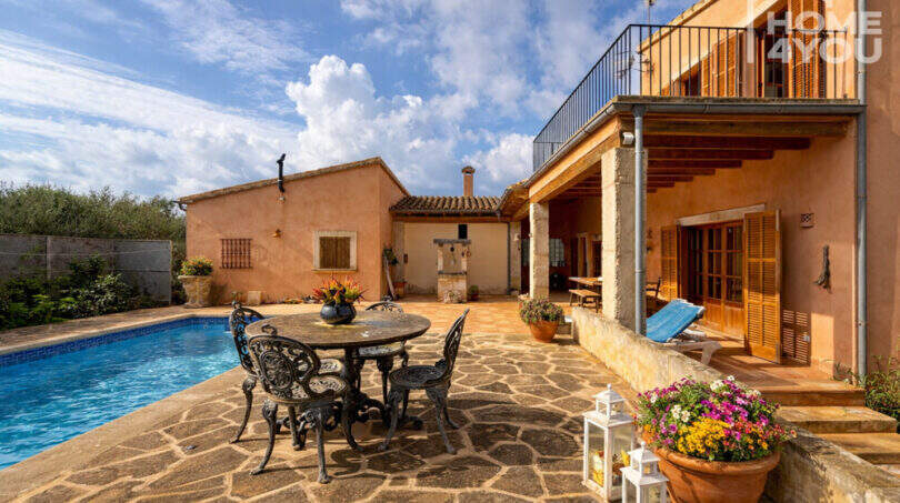 Finca Ses Salines: Sonnige Poolterrasse mit Naturstein, Schmiedeeisenmöbeln und rustikaler Fassade.