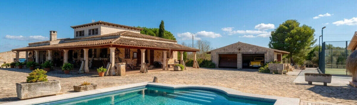Außenansicht mediterrane Finca Santa Margalida: großer Pool, überdachte Terrasse mit Säulen, Garage und Gartenanlage.