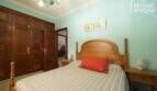 Schlafzimmer der Finca mit Holzbett, mintgrünen Wänden, Einbauschränken und dekorativem Kronleuchter.