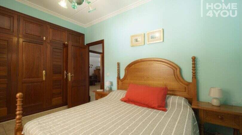 Schlafzimmer der Finca mit Holzbett, mintgrünen Wänden, Einbauschränken und dekorativem Kronleuchter.