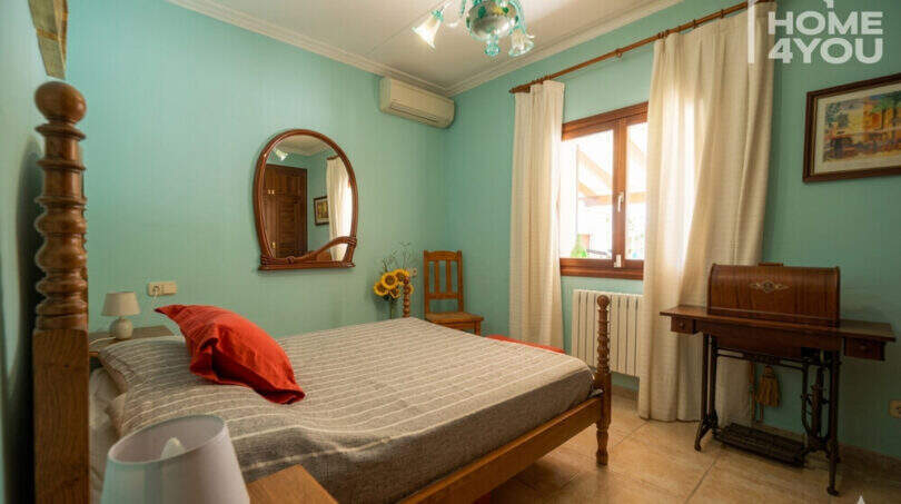 Schlafzimmer der Finca in Santa Margalida mit Holzbett, türkisfarbenen Wänden und antikem Schreibtisch