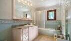 Helles Badezimmer der Finca mit Badewanne, Dusche, Waschtischunterschrank und dekorativen Fliesenbordüren.