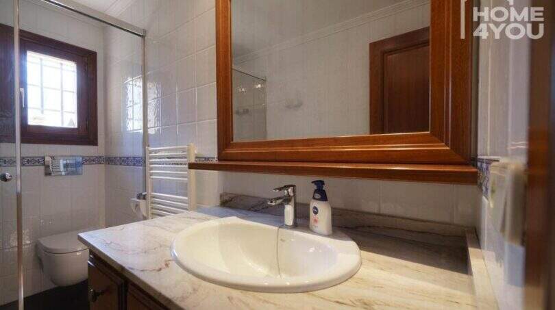 Badezimmer der Finca mit Marmorwaschtisch, Holzspiegel, Dusche und Heizkörper in Santa Margalida