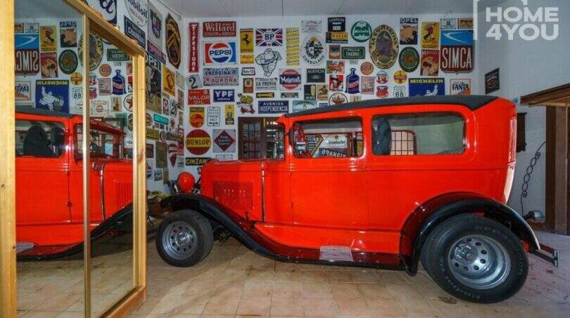 Garage der Finca mit rotem Oldtimer und nostalgischen Werbeschildern an der Wand