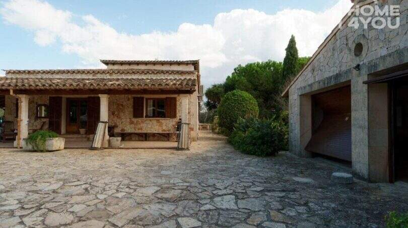 Außenansicht mediterrane Finca Santa Margalida: Natursteinhaus mit Terrakottadach, Garage und gepflastertem Innenhof