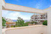 Penthouse-Terrasse in Cala d'Or mit Meerblick, weißen Fassaden und mediterranem Grün unter blauem Himmel.