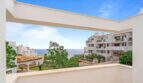 Penthouse-Terrasse in Cala d'Or mit Meerblick, weißen Fassaden und mediterranem Grün unter blauem Himmel.