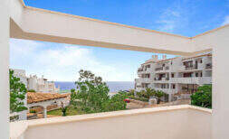 Penthouse-Terrasse in Cala d'Or mit Meerblick, weißen Fassaden und mediterranem Grün unter blauem Himmel.