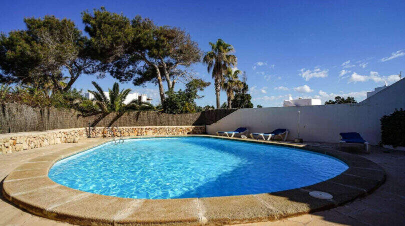 Ovaler Außenpool mit Steinumrandung, Liegestühlen und Palmen in der Ferienanlage Cala d'Or, Santanyí
