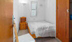 Kleines Schlafzimmer im Penthouse Cala d'Or mit Doppelbett, Holzmöbeln und natürlichem Licht