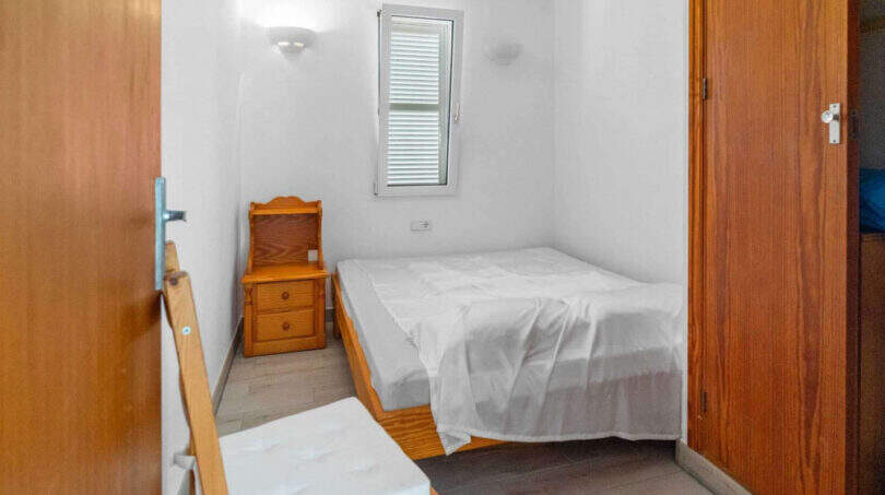 Kleines Schlafzimmer im Penthouse Cala d'Or mit Doppelbett, Holzmöbeln und natürlichem Licht