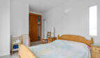 Helles Schlafzimmer im Penthouse Cala d'Or mit Holzbett, Einbauschrank und weißen Wänden