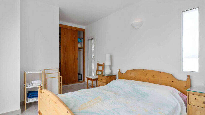 Helles Schlafzimmer im Penthouse Cala d'Or mit Holzbett, Einbauschrank und weißen Wänden