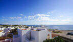 Panoramablick auf weiße Ferienhäuser in Cala d'Or mit türkisblauem Mittelmeer und klarem Himmel