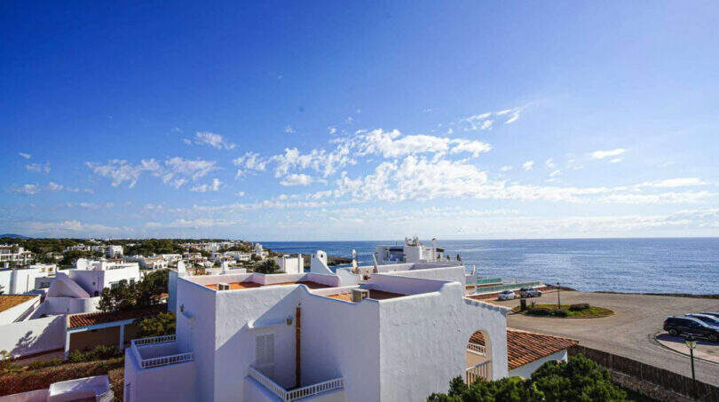 Panoramablick auf weiße Ferienhäuser in Cala d'Or mit türkisblauem Mittelmeer und klarem Himmel