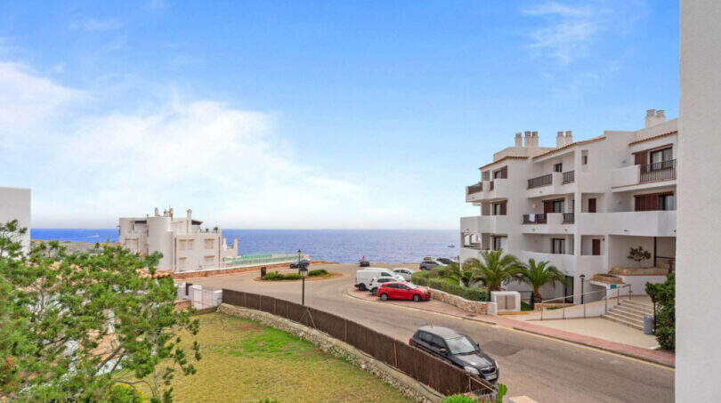 Außenansicht des Penthouse in Cala d'Or mit Meerblick, weißen Apartmentgebäuden und Parkplatz