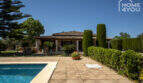 Mediterranes Finca-Außenbereich in Lloseta mit Pool, Terrasse, Zypressen und Blick auf das Hauptgebäude.