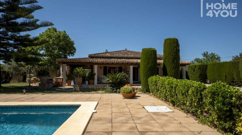Mediterranes Finca-Außenbereich in Lloseta mit Pool, Terrasse, Zypressen und Blick auf das Hauptgebäude.