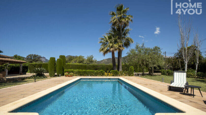 Rechteckiger Pool mit Natursteinumrandung, Palmen und Bergblick der Finca in Lloseta