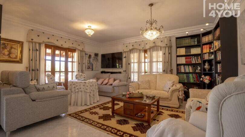 Elegantes Wohnzimmer der Finca in Lloseta mit Kronleuchtern, Sofagruppe, Bücherregal und mediterranem Charme.