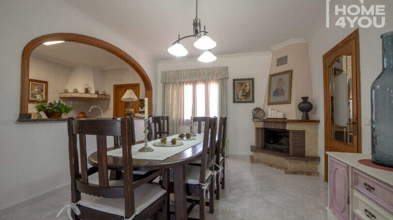 Esszimmer der Finca in Lloseta mit Holztisch, Kamin, Bogendurchgang zur Küche und mediterranem Charme.
