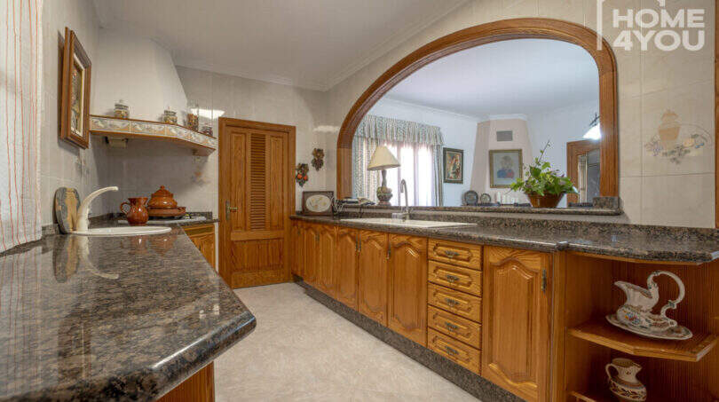 Mediterrane Küche mit Holzschränken, Granitarbeitsplatten und elegantem Rundbogen-Durchreiche in Finca Lloseta.