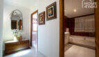 Flur mit Holzkommode, Spiegel & Blick ins Bad mit Marmorbadewanne der Finca in Lloseta