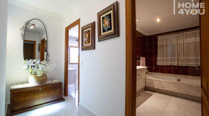 Flur mit Holzkommode, Spiegel & Blick ins Bad mit Marmorbadewanne der Finca in Lloseta