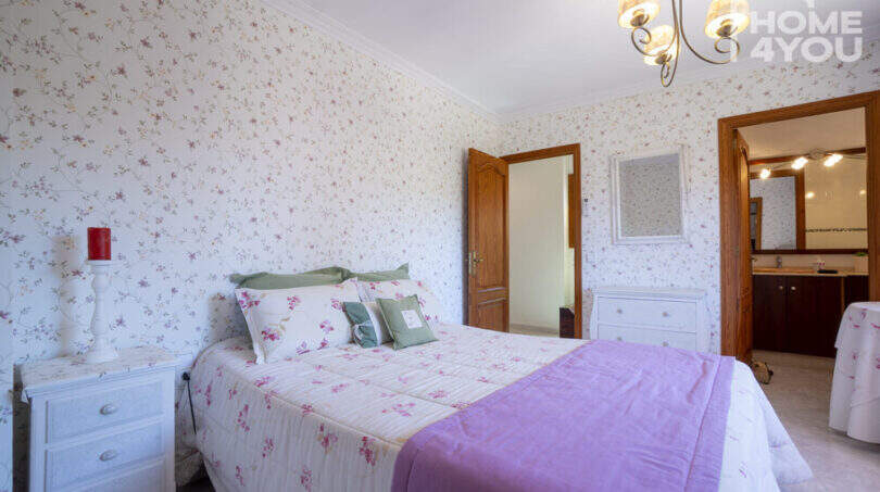 Romantisches Schlafzimmer mit Blumentapete, Doppelbett, Einbaubad und Kronleuchter in Finca Lloseta