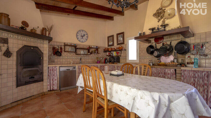Rustikale Landhausküche mit Holzbalkendecke, Steinofen, Esstisch und traditionellen Fliesen in Finca Lloseta