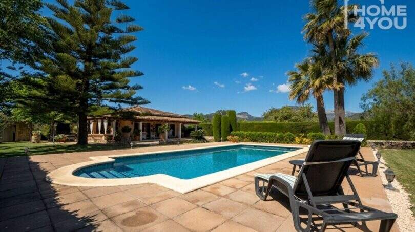 Mediterrane Finca in Lloseta: Großer Pool mit Liegestühlen, Palmen und Bergpanorama im Hintergrund.