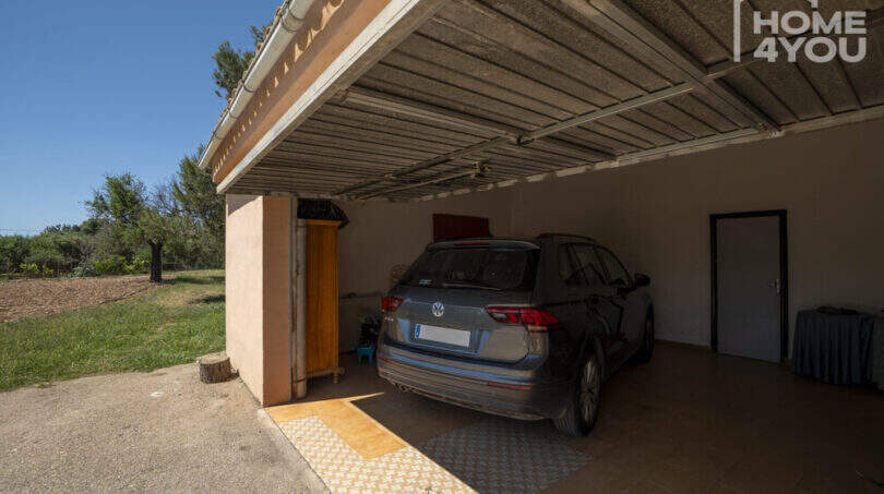 Geräumige Garage der Finca in Lloseta mit VW-SUV, Überdachung und Zugang zum Innenbereich.