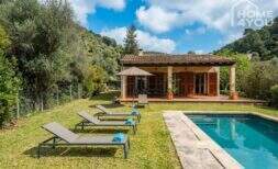 Finca Campanet: Poolbereich mit Liegestühlen, Rasengar­ten und mediterranem Landhaus in grüner Naturlage