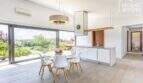 Open living-dining area with modern kitchen, glass front and garden view of the Mediterranean finca in Sa Pobla