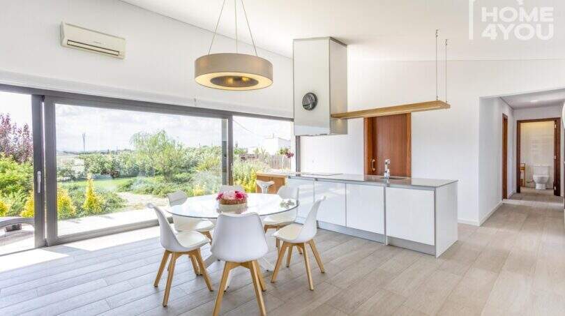 Open living-dining area with modern kitchen, glass front and garden view of the Mediterranean finca in Sa Pobla