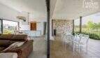 Open living-dining area with terrace, white kitchen and natural stone wall of the Mediterranean finca in Sa Pobla