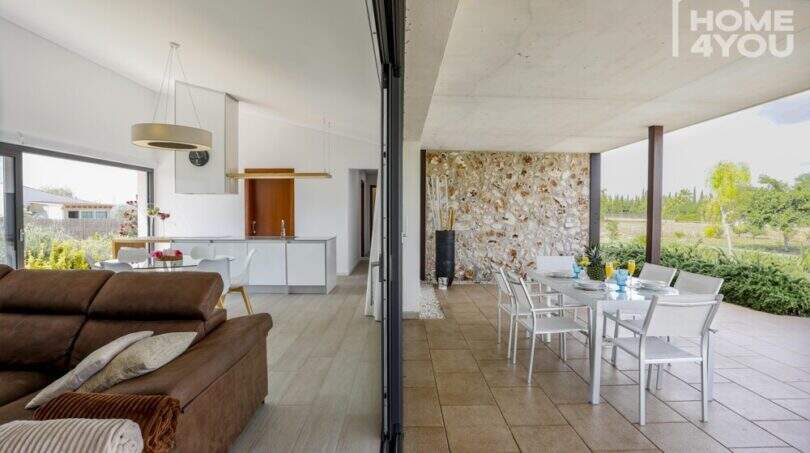 Open living-dining area with terrace, white kitchen and natural stone wall of the Mediterranean finca in Sa Pobla