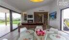 Light-filled living room of the finca in Sa Pobla with glass doors, fireplace and panoramic garden view