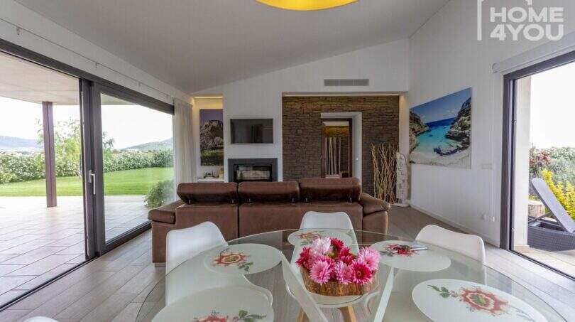 Light-filled living room of the finca in Sa Pobla with glass doors, fireplace and panoramic garden view
